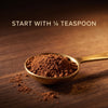 A small gold spoon filled with brown powder sits on a wooden surface, with scattered powder nearby and the text 'START WITH 1/4 TEASPOON' at the top.