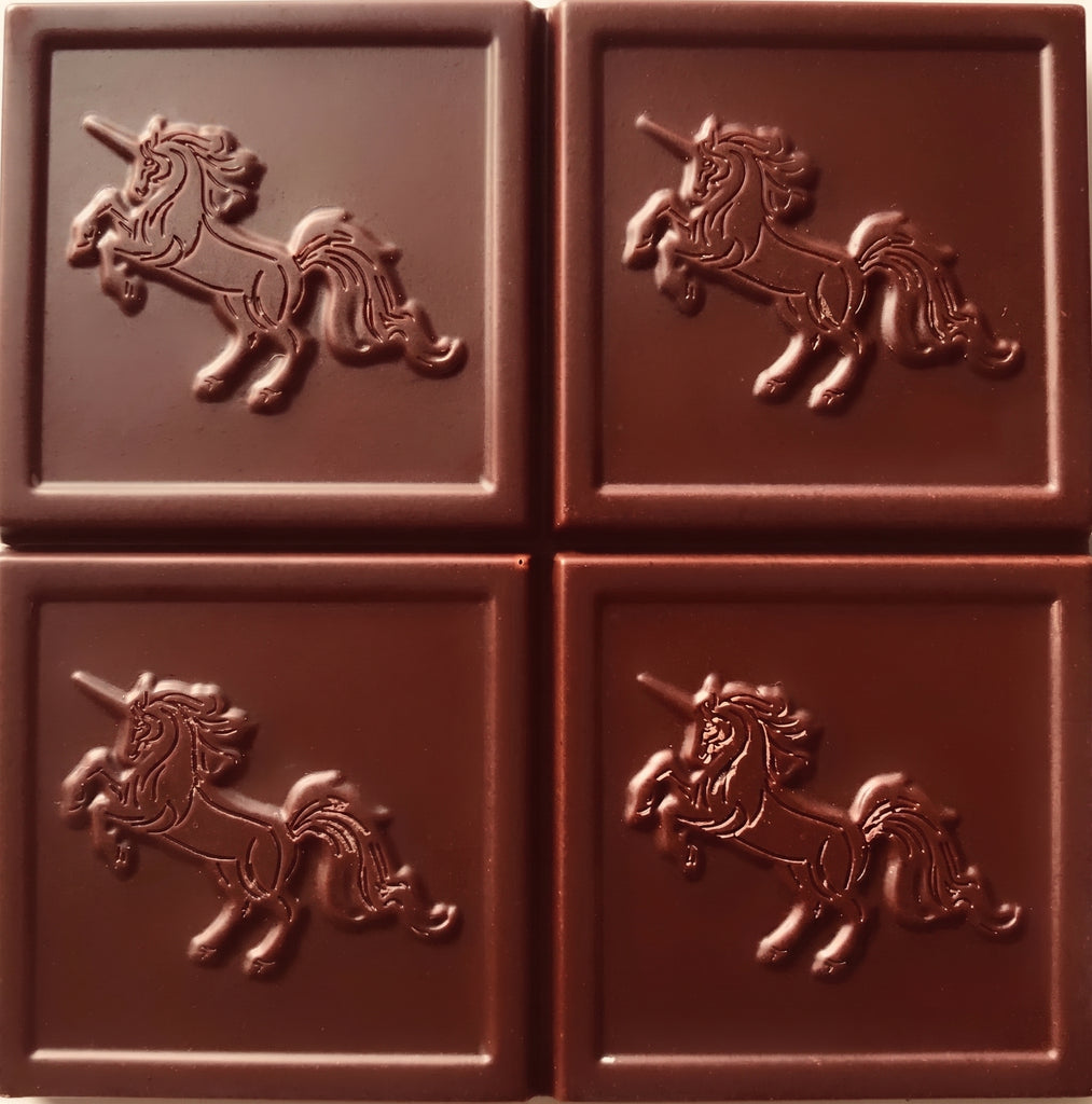 Four dark brown chocolate squares arranged in a 2x2 grid, each embossed with a raised unicorn design.