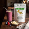 Addictive Wellness Pine Pollen pouch next to a berry smoothie topped with pine pollen