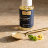 One serving of liposomal glutathione in a brass spoon with the Lemon Mint bottle behind it