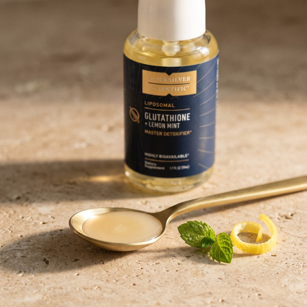 One serving of liposomal glutathione in a brass spoon with the Lemon Mint bottle behind it