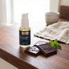 Liposomal Glutathione Cacao Mint bottle beside squares of Addictive Wellness unicorn chocolate and fresh mint