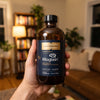 Hand holding a bottle of Quicksilver Liposomal Magtein in a cozy living room