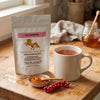 Addictive Wellness Schizandra pouch beside a mug of rosy schizandra tea, a dish of powder and fresh berries